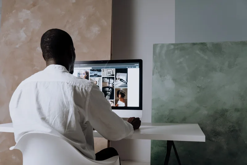 A man sitting at a computer workstation, representing a visitor spending time on a personal brand’s About page